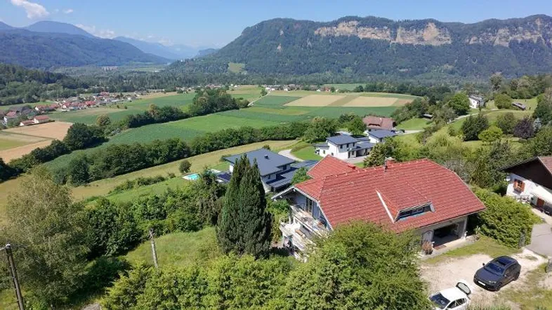 Panoramablick auf ein Haus mit rotem Dach, umgeben von grünen Hügeln und einem weiten Tal.