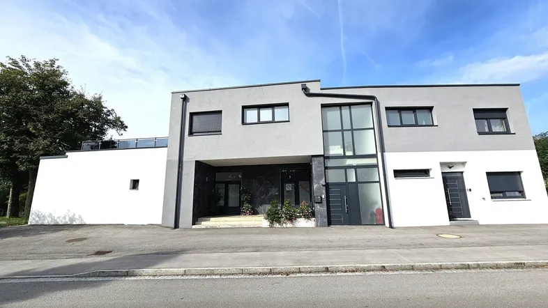 Moderne Architektur mit grauer und weißer Fassade sowie großen Fenstern.