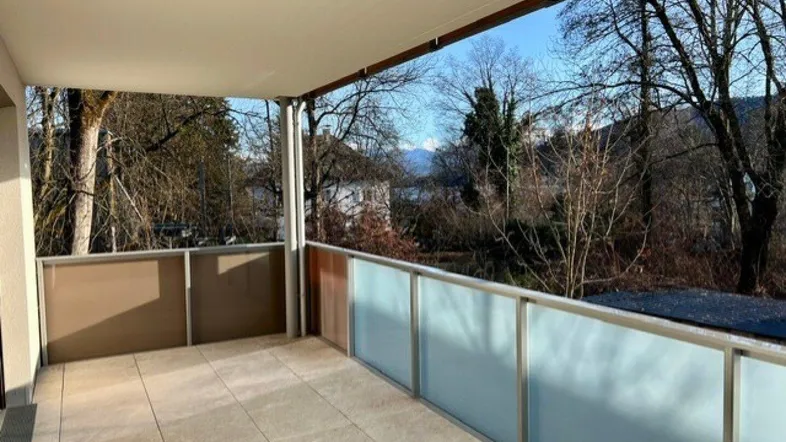 Geräumiger Balkon mit Fliesenboden und weitem Blick ins Grüne und auf die Berge.
