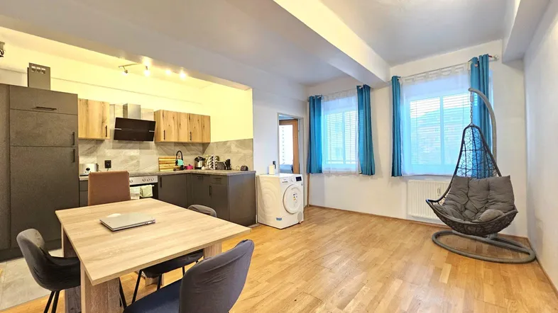 Geräumiger offener Wohn- und Essbereich mit integrierter Küche, Holzboden und Waschmaschine.