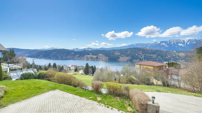 Weitläufiger Blick über einen See und die umliegende Berglandschaft unter einem klaren blauen Himmel.