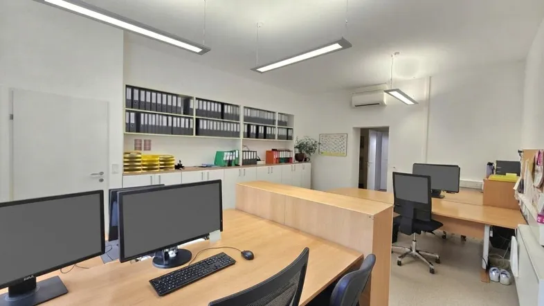 Helles und geräumiges Büro mit mehreren Arbeitsplätzen, Aktenschränken und Klimaanlage.