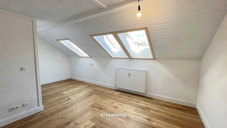 Heller Raum im Dachgeschoss mit Holzboden, Dachfenstern und schräger Decke.
