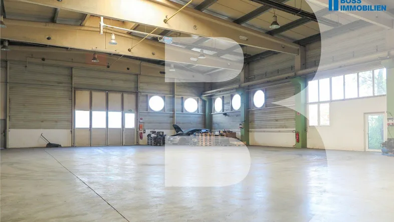 Geräumige Lagerhalle mit hohen Decken, Betonboden und großen Fenstern, bereit zur Nutzung.