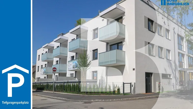 Modernes Mehrfamilienhaus mit weißer Fassade, großen Fenstern und mehreren Balkonen.