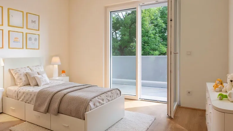Helles Schlafzimmer mit Holzboden, weißem Bett und Zugang zu einem Balkon mit Blick ins Grüne.