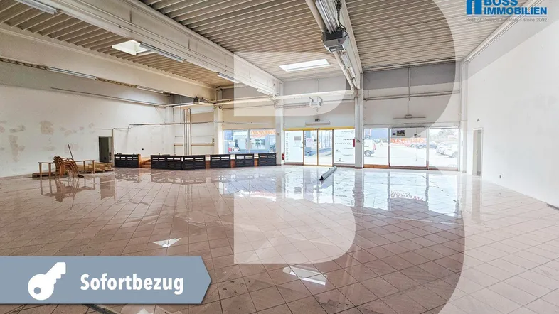 Großer, leerstehender Gewerberaum mit Fliesenboden, hohen Decken und viel Tageslicht durch große Fenster.