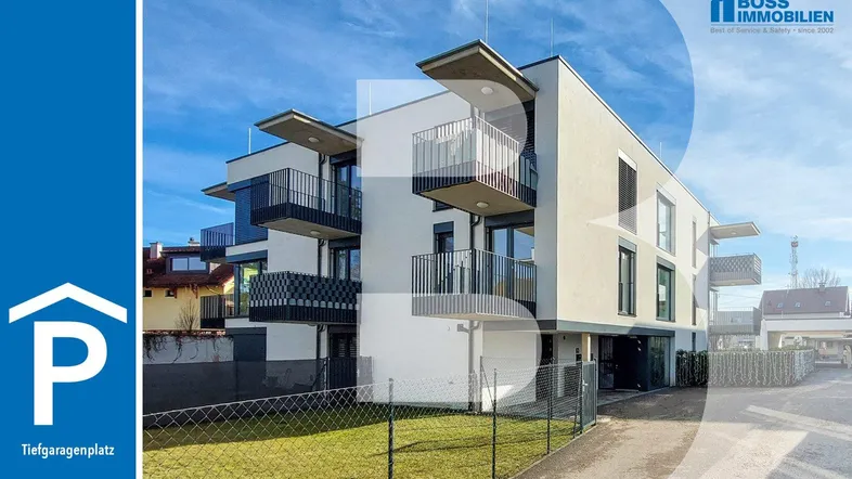 Modernes Mehrfamilienhaus mit Balkonen und gepflegter Grünfläche, inklusive Hinweis auf Tiefgaragenplatz.