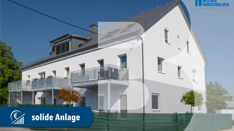 Modernes Mehrfamilienhaus mit weißer und grauer Fassade sowie Balkonen unter blauem Himmel.