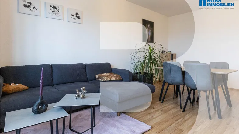 Gemütlicher Wohn-Essbereich mit dunklem Sofa, Esstisch und hellem Holzboden, ideal für entspannte Stunden.