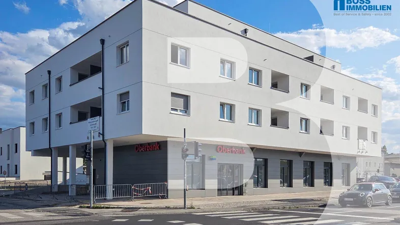 Modernes Mehrfamilienhaus mit weißer Fassade, Geschäftsflächen im Erdgeschoss und Wohnungen mit Loggien in den oberen Etagen.