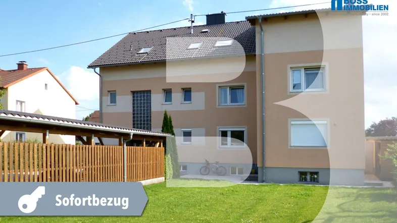 Mehrfamilienhaus mit Gartenbereich und überdachtem Stellplatz im Freien.