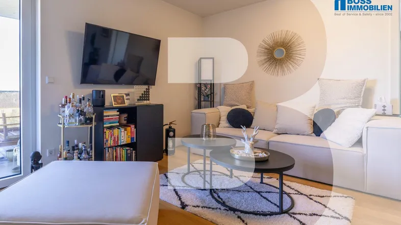 Helles Wohnzimmer mit modernem Sofa, Fernseher und Zugang zu einem Außenbereich.