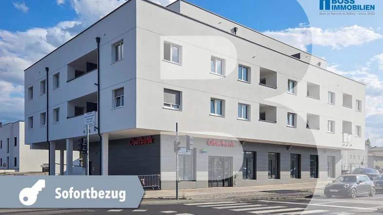 Modernes Mehrfamilienhaus mit weißer Fassade, Flachdach und integrierten Balkonen in städtischer Umgebung.