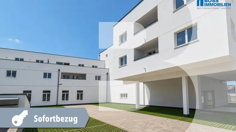 Modernes, weißes Mehrfamilienhaus mit klaren Linien und überdachten Parkplätzen im Freien.