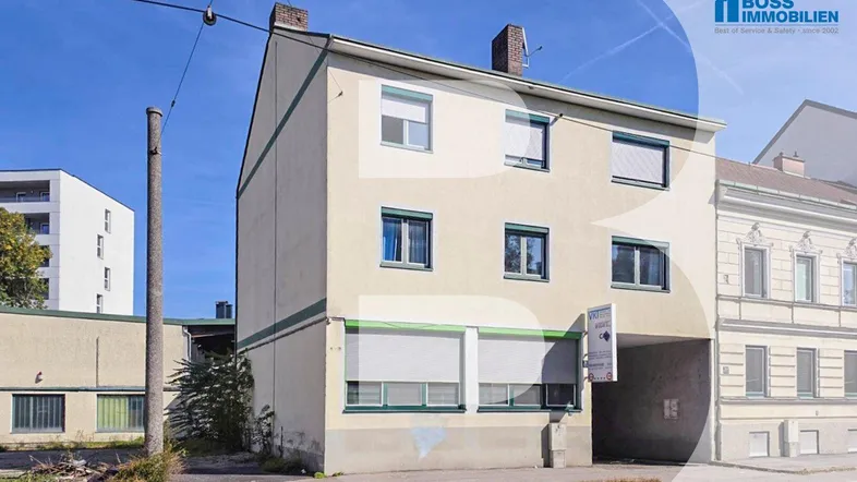 Gebäudeansicht eines Mehrfamilienhauses mit mehreren Fenstern und einem Durchgang.