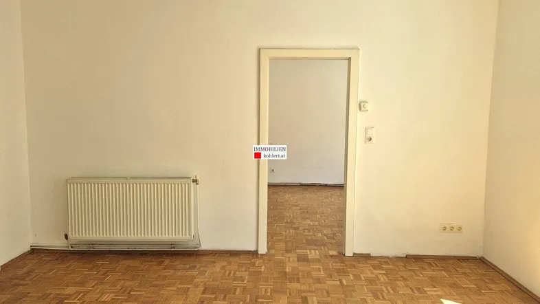 Helles, leeres Zimmer mit Parkettboden und Heizkörper, bereit zur individuellen Gestaltung.