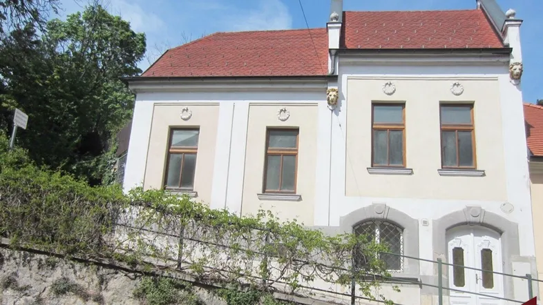 Altes Gebäude mit heller Fassade, roten Ziegeldächern und dekorativen Elementen.