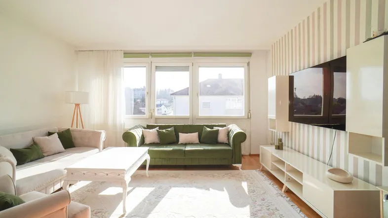 Helles Wohnzimmer mit bequemen Sofas, Parkettboden und Blick ins Grüne.