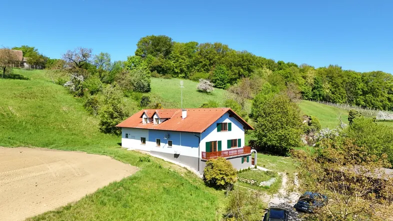 Ländliches Anwesen mit Einfamilienhaus und weitläufiger grüner Umgebung unter blauem Himmel.