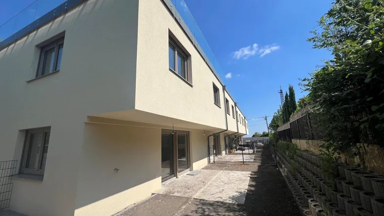 Moderne Reihenhäuser mit heller Fassade und potenzieller Terrassenfläche im Freien.