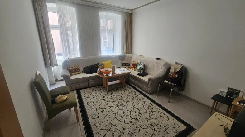Helles Wohnzimmer mit gemütlichem Ecksofa, Teppich und Blick auf die Straße.
