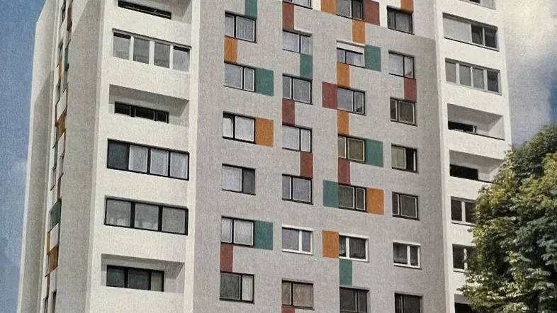Modernes Mehrfamilienhaus mit farbiger Fassadengestaltung und zahlreichen Fenstern sowie Balkonen.