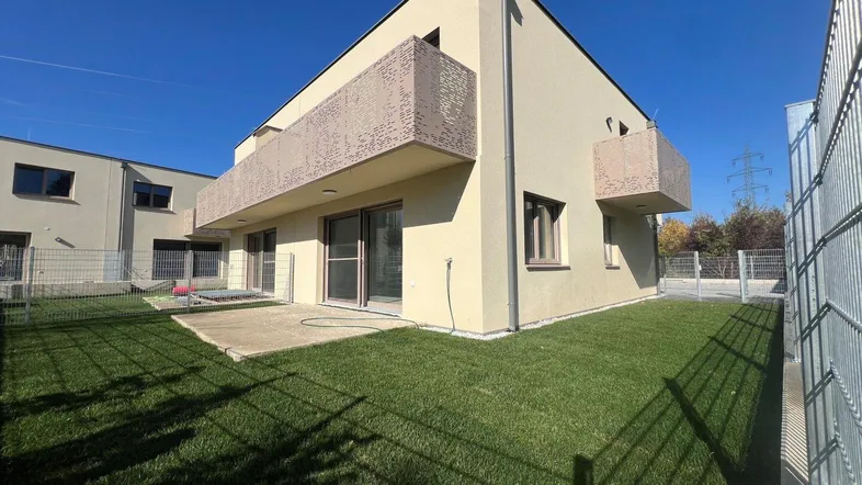 Modernes Einfamilienhaus mit gepflegtem Garten, Terrasse und Balkonen unter blauem Himmel.