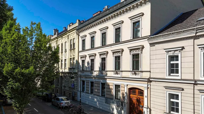 Historisches Gebäude mit klassischer Fassade und Blick auf die Baumallee.