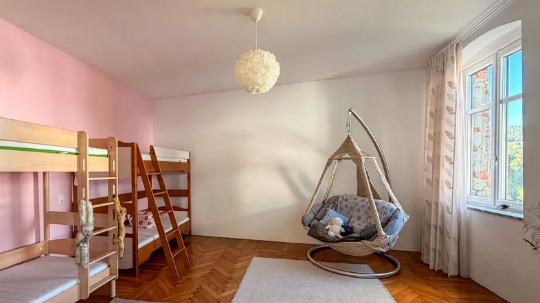 Helles Schlafzimmer mit Etagenbetten, einem Hängesessel und Parkettboden, ideal für Kinder oder Gäste.
