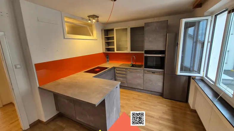 Moderne Küche mit Holzparkettboden, orangefarbener Rückwand und integrierten Geräten.