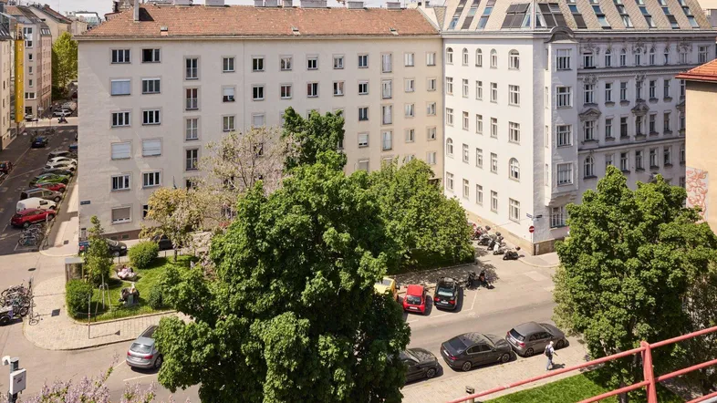 Blick von oben auf eine städtische Wohngegend mit Bäumen, Gebäuden und parkenden Autos.