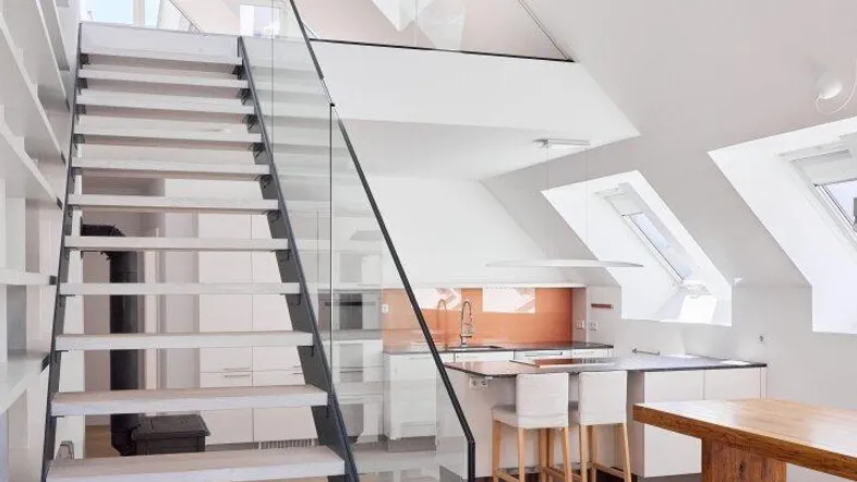 Moderner offener Wohnbereich mit eleganter Treppe, Glasgeländer und vielen Dachfenstern für viel Licht.