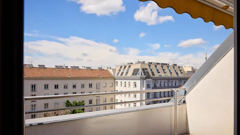 Blick vom Balkon auf die umliegenden Gebäude und den blauen Himmel mit Wolken.
