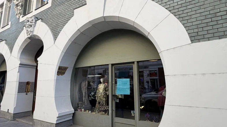 Fassade eines historischen Gebäudes mit markanten Bögen und einem Ladengeschäft im Erdgeschoss.
