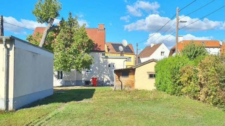 Großer Gartenbereich mit Rasenfläche und Blick auf umliegende Gebäude unter blauem Himmel.