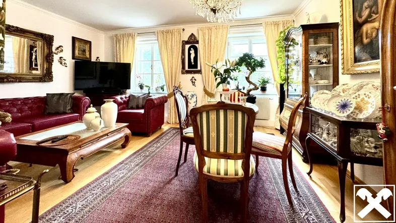 Geräumiges Wohnzimmer mit klassischen roten Ledersofas, Kronleuchter und elegantem Teppichboden.