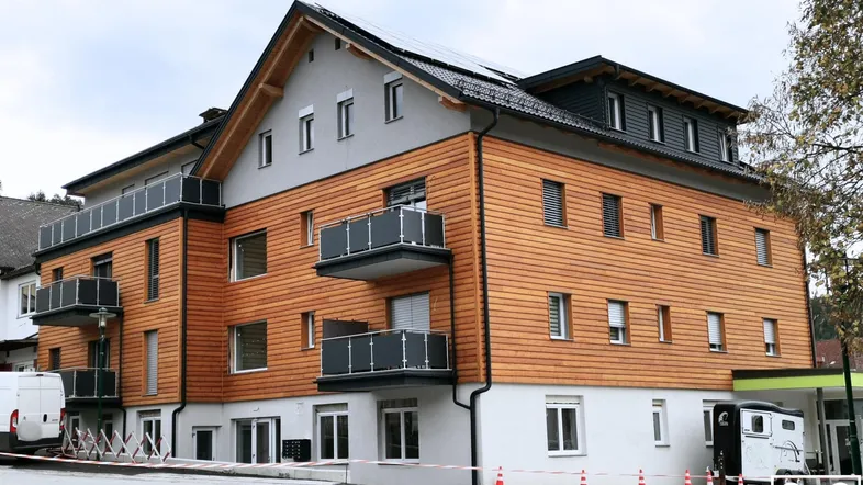 Modernes Mehrfamilienhaus mit Holzfassade, Balkonen und Photovoltaikanlage auf dem Dach.