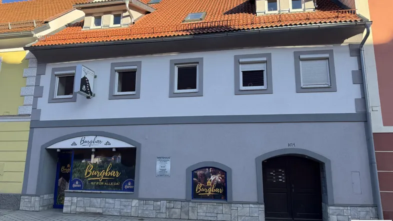Fassade eines Gebäudes mit Geschäften im Erdgeschoss und Wohnungen darüber in einer städtischen Umgebung.