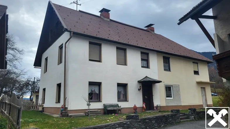 Traditionelles Wohnhaus mit Satteldach und weißer Fassade in ländlicher Umgebung.