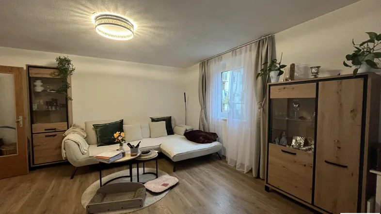 Gemütliches Wohnzimmer mit beigem Sofa, Holzelementen und pflegeleichtem Laminatboden.