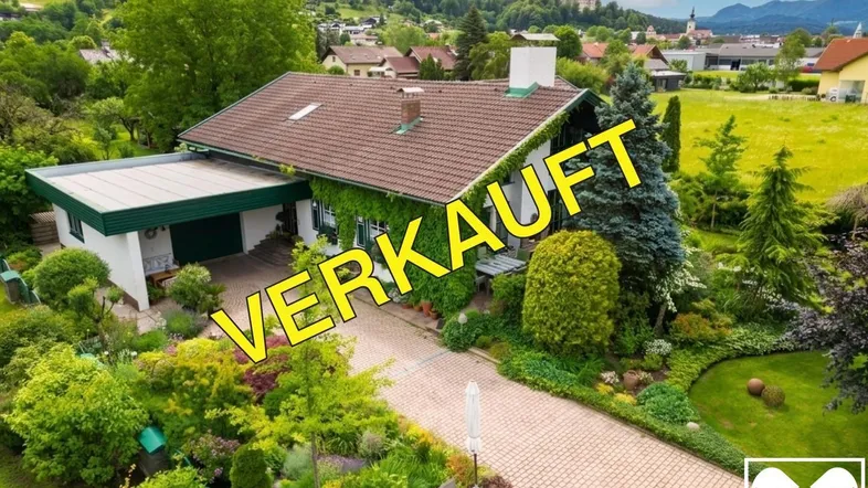 Luftaufnahme eines gepflegten Einfamilienhauses mit großem Garten, Terrasse und Bergblick, bereits verkauft.
