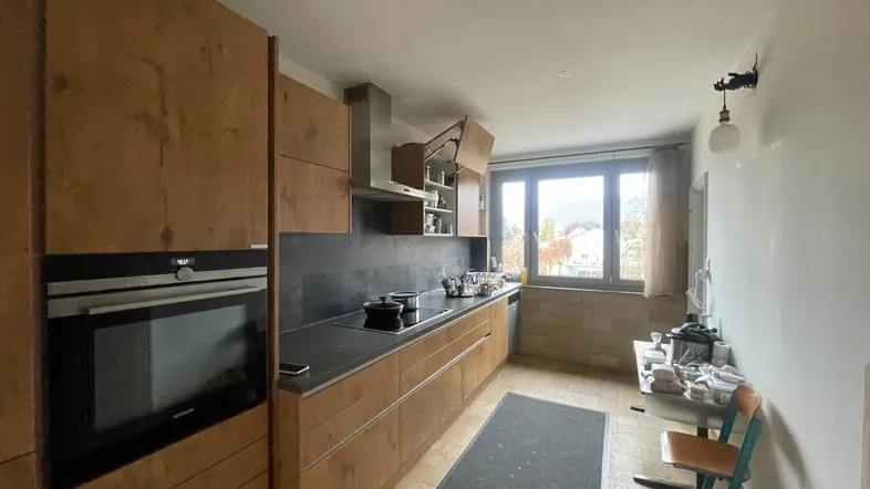 Funktionale Küche mit Holzfronten, integriertem Backofen und Blick nach draußen.