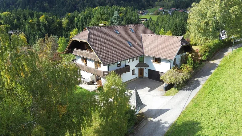 Großzügiges Einfamilienhaus in ländlicher Umgebung mit Satteldach und Balkonen, umgeben von viel Grün.