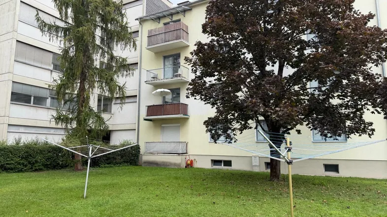 Blick auf die Gebäudefassade mit mehreren Balkonen und einem gepflegten Rasenbereich im Vordergrund.