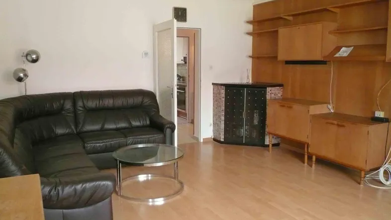 Geräumiges Wohnzimmer mit Lederecksofa, Holzwandverbau und einem Kaminofen.