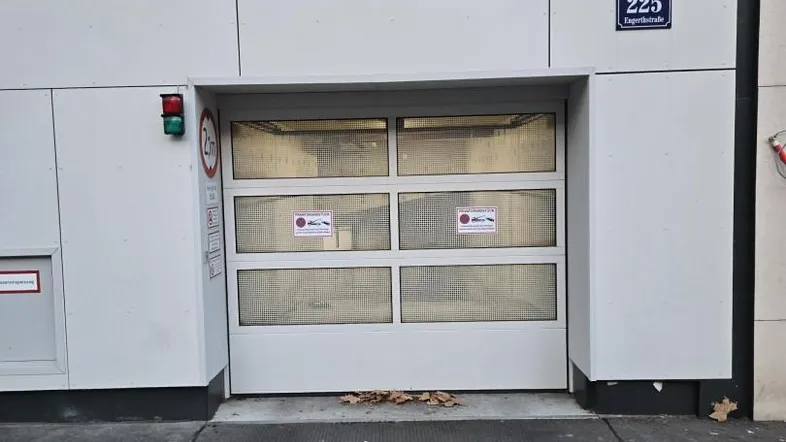 Moderner Eingang zur Tiefgarage mit Rolltor und Hausnummer 225 an der Fassade.