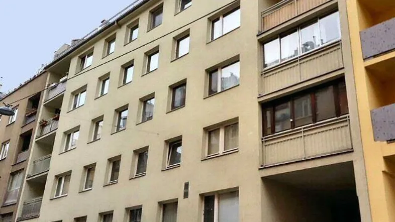 Mehrstöckiges Wohngebäude mit beiger Fassade und Balkonen in städtischer Umgebung.