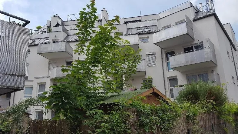 Mehrfamilienhaus mit mehreren Balkonen und Dachterrassen in städtischer Umgebung.