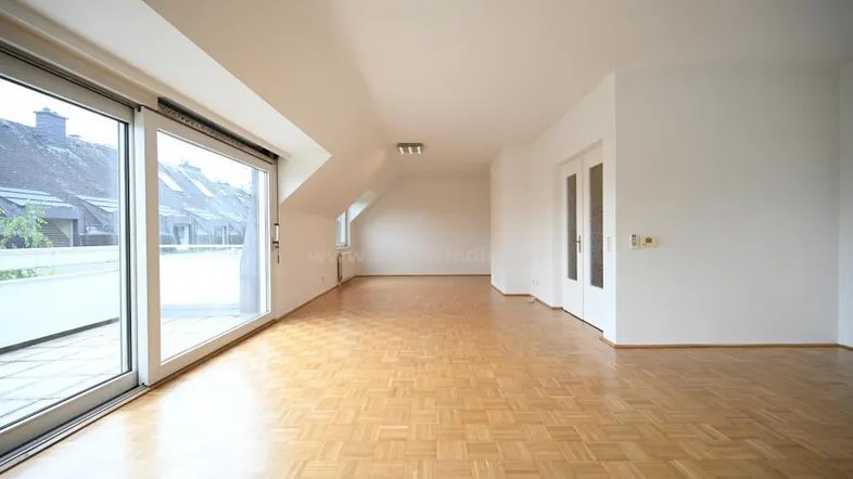 Helles, geräumiges Zimmer mit Parkettboden und Zugang zu einem Balkon oder einer Terrasse.